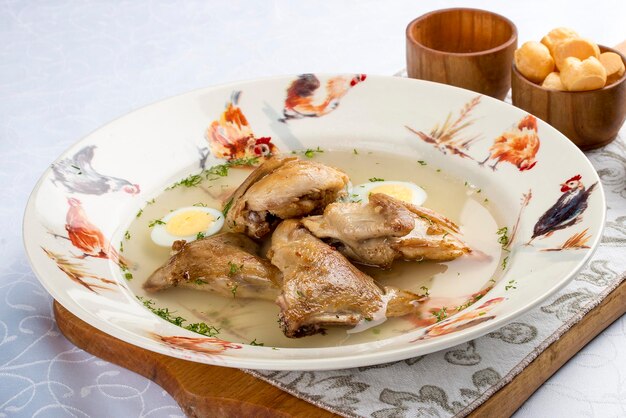 Quail broth with crackers and herbs on a wooden board On white background