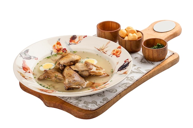 Quail broth with crackers and herbs on a wooden board On white background