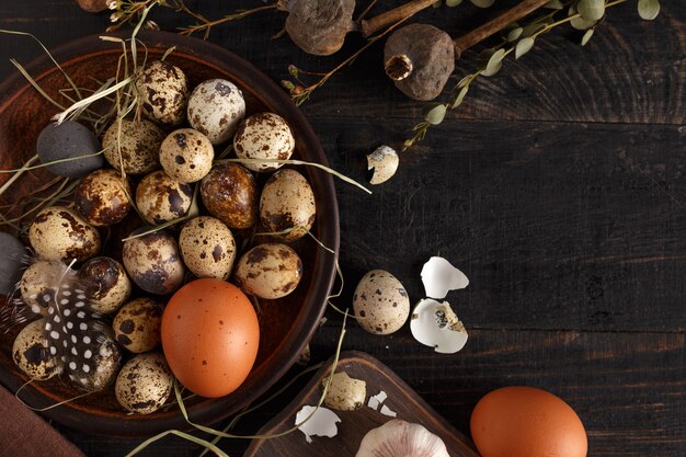 Quail and chicken eggs on a clay plate on a dark wooden surface.