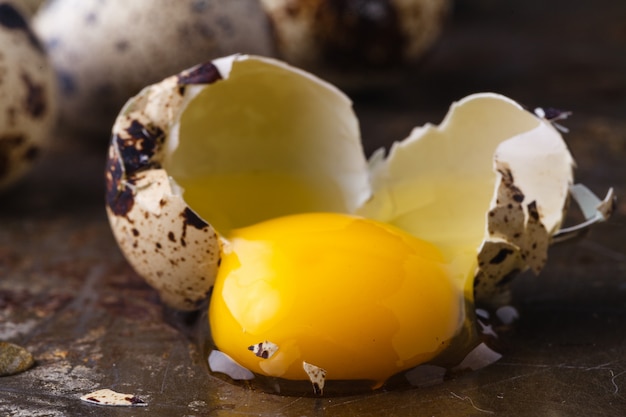 Quail egg broken on rustic table