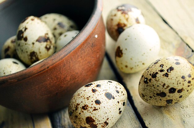The quail eggs in a brown bowl on wooden surface