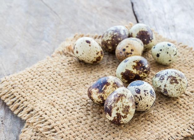 Quail eggs in burlap sack on a wooden table