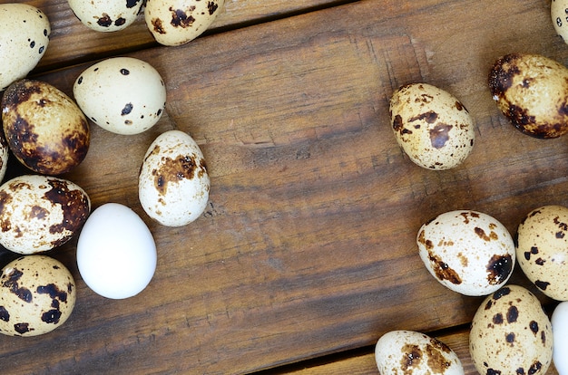 Quail eggs on a dark brown wooden surface, top view, empty place for text, recipe