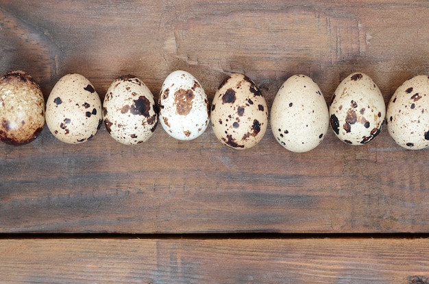 Quail eggs on a dark brown wooden surface, top view, empty place for text, recipe