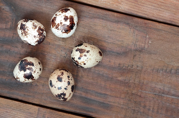 Quail eggs on a dark brown wooden surface, top view, empty place for text, recipe