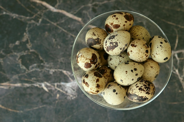 Quail eggs in a glass plate top view With a blurred marble background