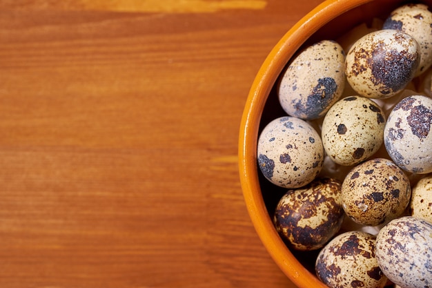 Фото Перепелиные яйца в глиняной миске на коричневом дереве