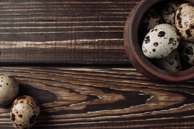 Quail eggs lie in a clay bowl and a couple of pieces fell out of the plate