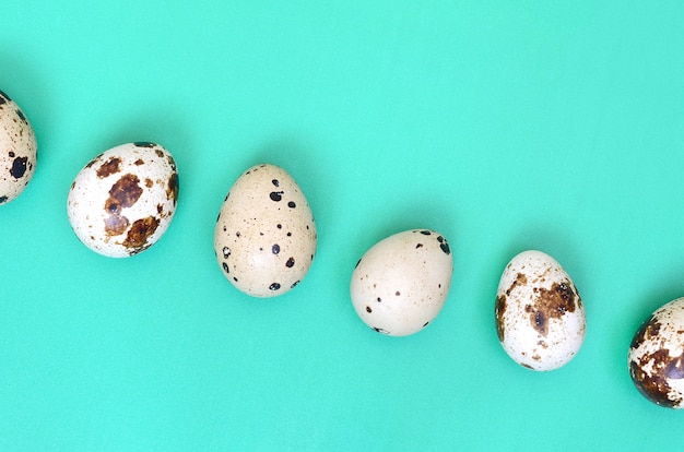 Quail eggs on a light green surface, top view, empty place for text, recipe