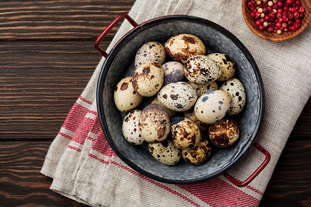 Quail eggs in metal plate on dark old surface. Rustic style