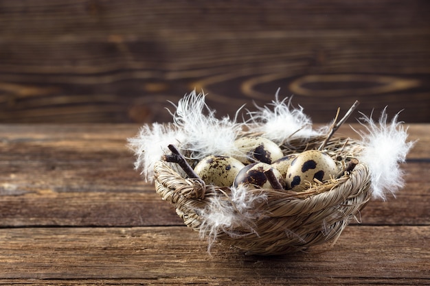 Quail eggs in a nest on a wooden table.