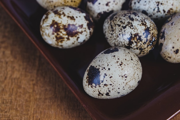 Перепелиные яйца в тарелку на фоне старого дерева таблицы.