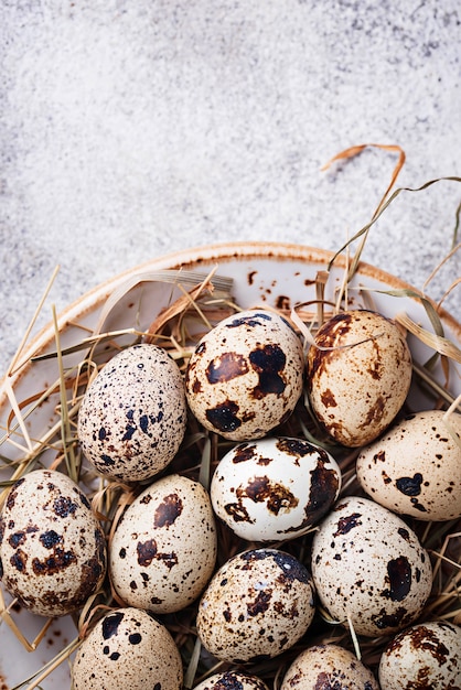 Quail eggs and straw on light background