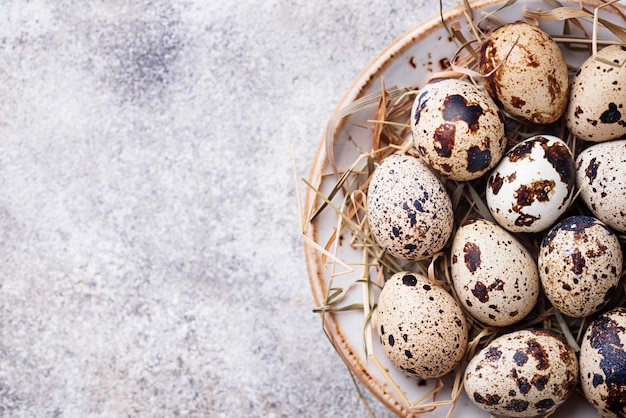 Quail eggs and straw on light background