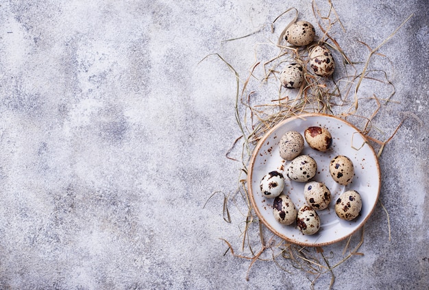 Quail eggs and straw on light background