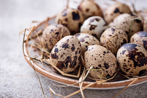 Quail eggs and straw on light background