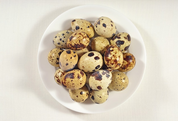 Quail eggs in a white bowl in a sacking background