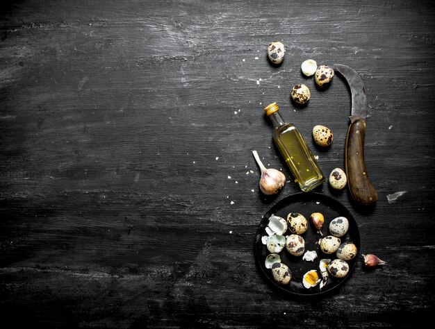 Quail eggs with olive oil and garlic on black wooden table.