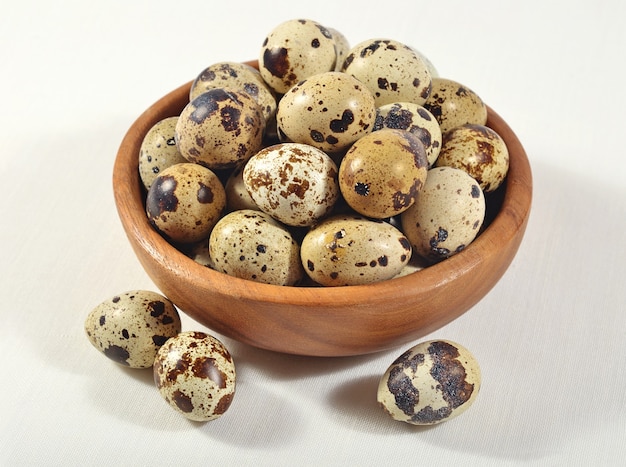 Quail eggs in a wooden bowl in a sacking background