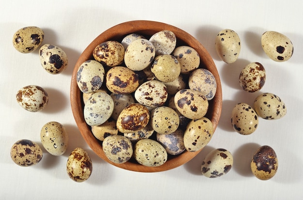 Quail eggs in a wooden bowl in a sacking background