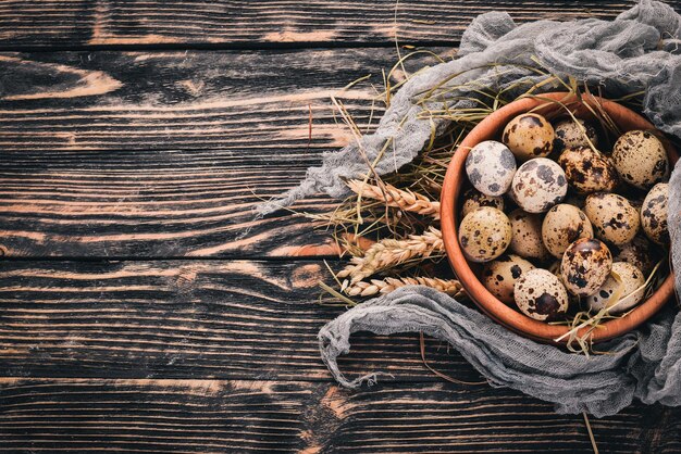 Quail eggs in a wooden bowl. On a wooden background. Top view. Copy space.