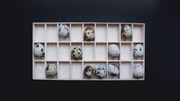 Uova di quaglia in contenitori di legno. vista dall'alto. sfondo nero