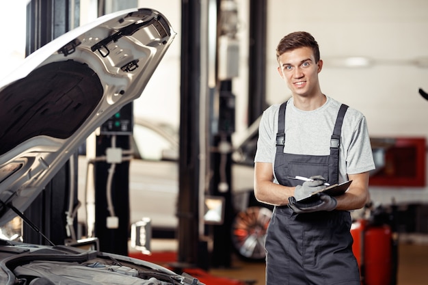 A qualified automechanic is at his work while checking an automobile.