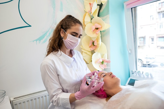 Qualified cosmetologist prepares the client's skin for mask application