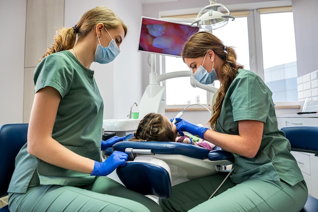 자격을 갖춘 치과 의사가 새로운 전문 장비로 어린이 치아를 검사합니다.