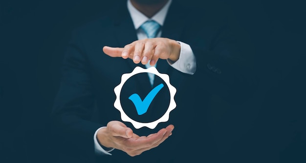 Quality assurance of business services businessman hand shows\
the sign of the top service quality assurance in black background\
guarantee standards iso certification and standardization\
concept