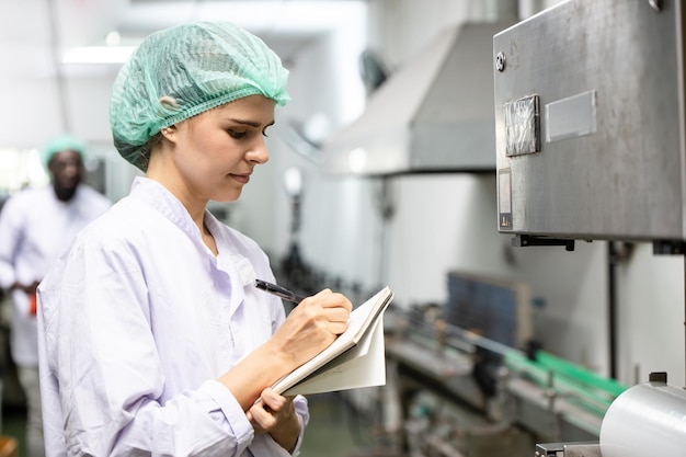 사진 품질 관리 및 식품 안전 백인 여성 노동자 직원은 식품 및 음료 공장 생산 라인의 제품 표준을 검사합니다.