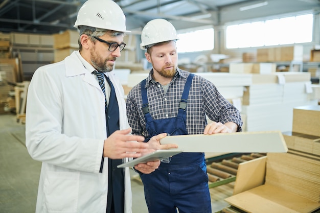 Quality control expert examining work of young engineer