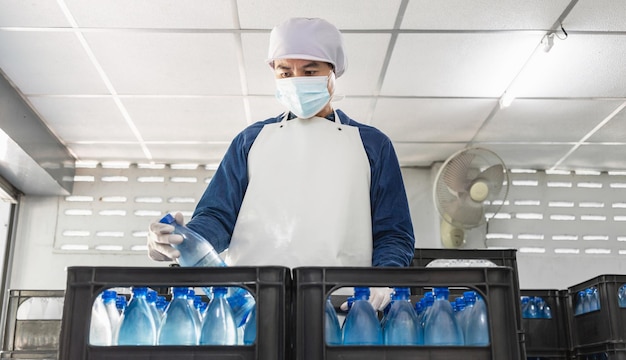 quality inspector  with a protective mask on his face working in checking bottled drinking water