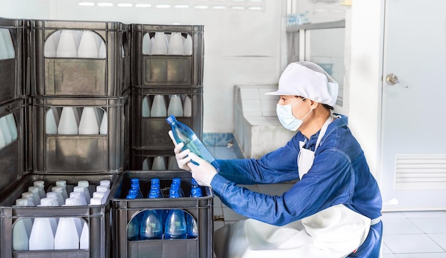 Quality inspector in workwear and with a protective mask on his face working in checking bottled