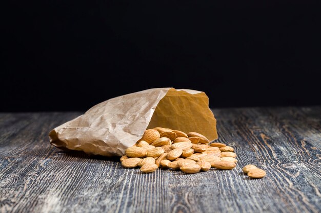 Quality raw nuts ready to eat, almonds on the kitchen table during cooking, almonds fresh and peeled, closeup, the surface of the nuts is not perfect , almonds in a paper bag