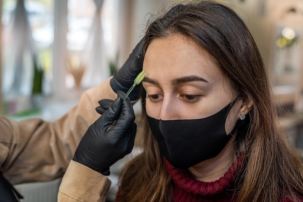 Quality skilled makeup artist girl doing eye makeup to a client
during an epidemic. the concept of makeup during the epidemic