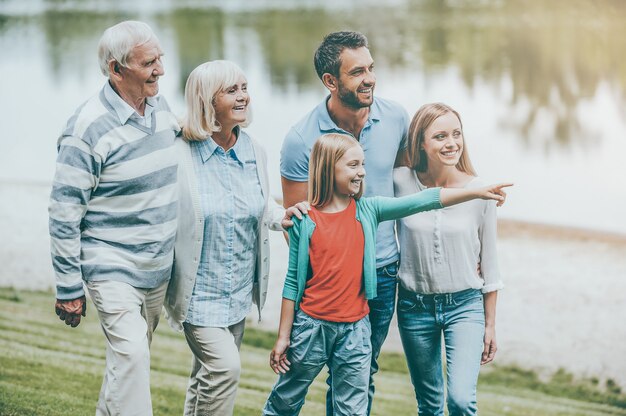 Quality time doorbrengen met familie. Gelukkige jonge familie die samen buiten loopt terwijl een klein meisje wegwijst en glimlacht