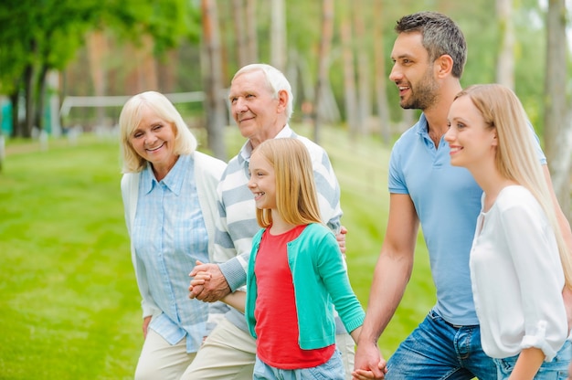 quality time with family. happy young family holding hands while walking outdoors together