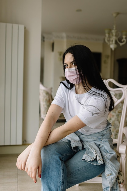 Quarantine Stay at home for the quarantine prevention of the coronavirus pandemic Sad girl in a protective medical mask sits and looks out the window Epidemic and Coveid Prevention19