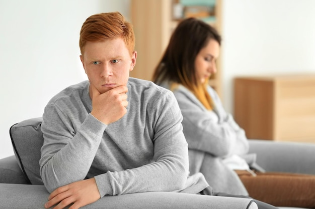 Photo quarrelled young couple sitting on sofa in light room