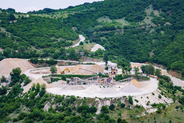 Quarry for extraction of minerals with equipment and machines and road in Rhodope Mountains covered with forests
