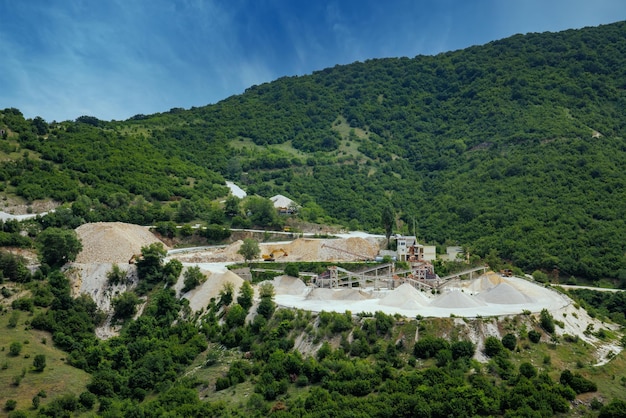 Quarry for extraction of minerals with equipment and machines and road in Rhodope Mountains covered with forests