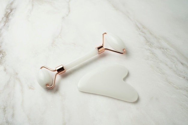 A quartz roller for face massage and gua sha for antiaging\
procedures in the form of the heart lying on a table