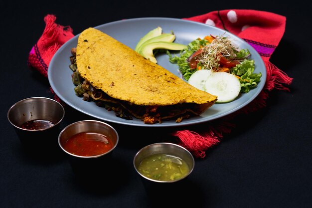 Quesadilla, Mexican food with avocado, salsa, and salad on black background. Meal.