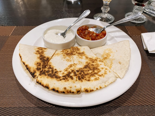 Quesadilla with sauce in plate on wooden plank