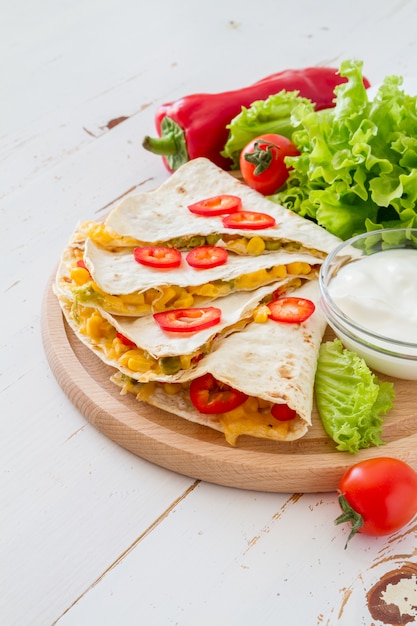 Quesadilla with sour cream, salad and tomatoes