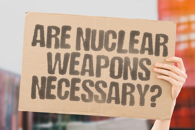 The question Are nuclear weapons necessary is drawn on a carton banner in men's hands Freedom Democracy Peace Unity Solidarity Awareness Propaganda Science Research Ethics Morality