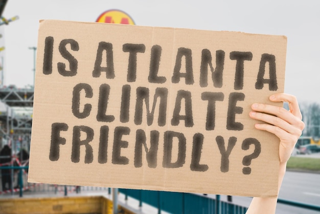 The question is atlanta climatefriendly is on a banner in men\'s\
hands with blurred background support team activist urban sunset\
carbon ecology energy new clean warming waste