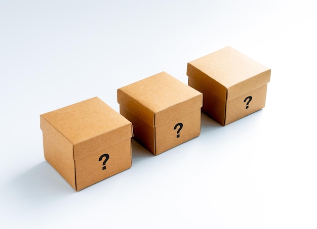 Question mark character icon on three closed cardboard boxes isolated on white background Square kraft paper box with lid on top Carton secret box mystery presents lucky deal concepts