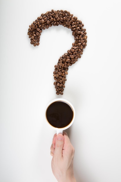 вопросительный знак, образованный настоящими кофейными зернами и чашкой кофе